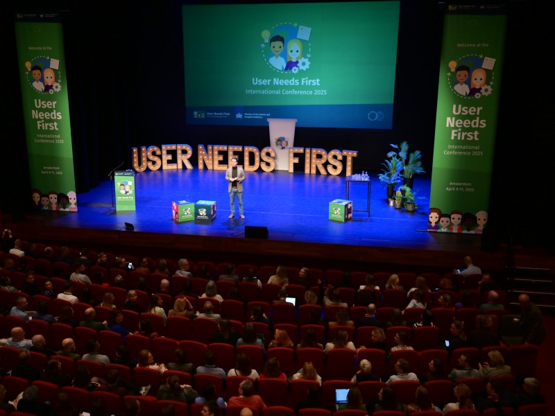 Podium User Needs First Conference 2025 met banieren en vouwkubussen